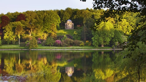 A view of the grounds at Stourhead, Wiltshire, with the Temple of Apollo in the distance reflecting in the lake